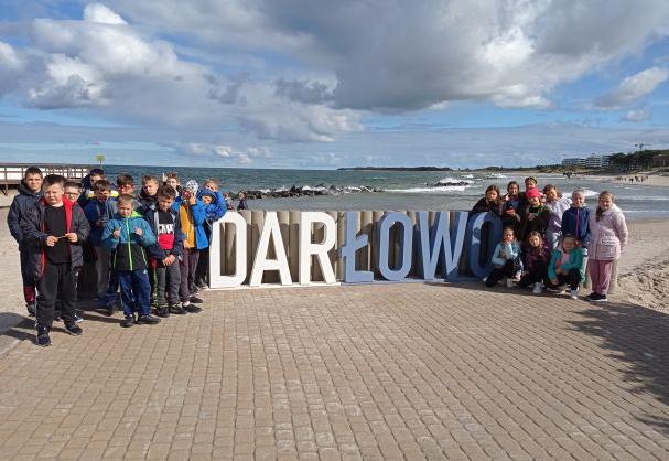 Dzieci stoją obok napisu Darłowo nad morzem